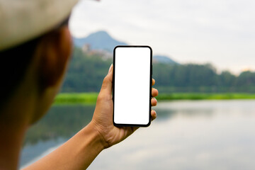 Man holding mobile phone with blank white desktop screen in the outdoor