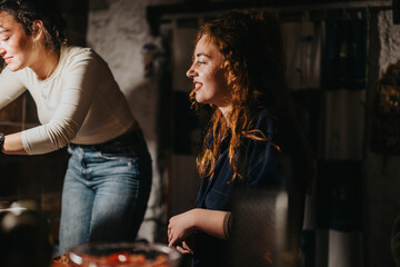 A candid moment of two women bonding and sharing a laugh in a cozy, homey kitchen environment with...