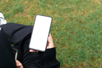 Woman holding mobile phone with blank white desktop screen in the outdoor