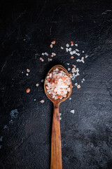 Himalayan salt in a wooden spoon on a dark background