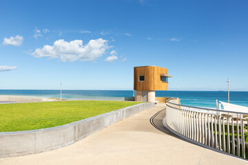 Scarborough beach lifeguard tower with curved fence and path foreground and clouds on a blue sky