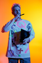 Creative expression of a young man in vibrant colors holding a notebook and pondering ideas