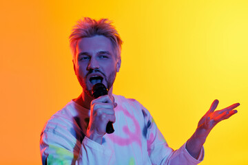 Young man passionately singing under vibrant colors in a lively atmosphere