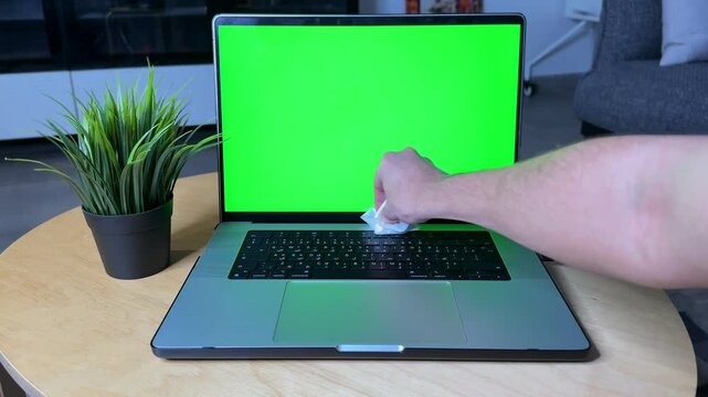 High-resolution 4K video of a person wiping a laptop trackpad with a visible green screen background&mdash;perfect for tech mockups, tutorials, and cleanliness themes.
