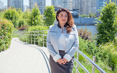 Fototapeta premium Confident Businesswoman in a Modern Cityscape. Street Style portrait of modern lady