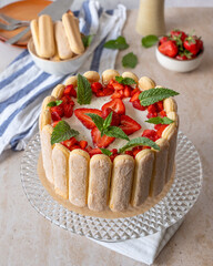 Charlotte cake with fresh strawberries and mint leaves. Homemade Charlotte cake decorated with cut strawberry and green mint 