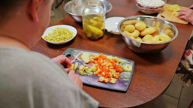 Potatoes and carrots chopped by hand for family-style Latvian rasols preparation
