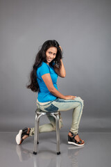 A young woman confidently poses wearing blue t-shirt, distressed denim jeans, heels, showcasing a...