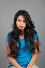 Fototapeta premium A young woman confidently poses wearing blue t-shirt, distressed denim jeans, heels, showcasing a casual urban style with charm and elegance, suitable for haircare, freedom, self-expression project