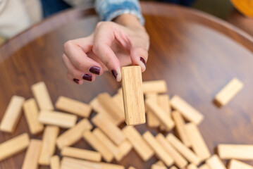 Happy asian diverse group friends playing with wooden building blocks at home office sitting at the table enjoying time together. Office leisure and board games concept.