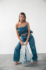 Stylish model poses in denim outfit with casual confidence in minimalistic studio setting