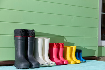 Colorful Rubber Boots Lined Up Against Green Wall