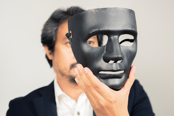 Businessman holding a black opera mask. The concept of a liar, dishonest person