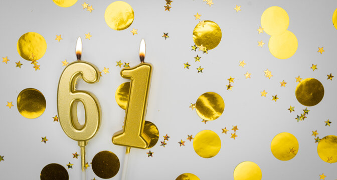 Number 61 golden celebration birthday candle on white with confetti Background. sixty-one years birthday. concept of celebrating birthday, anniversary