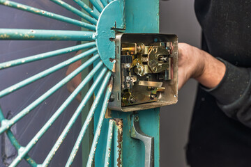 Male handyman carpenter installing mortise lock, closeup photo. Hands installing surface lock,...
