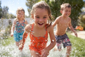 Children joyfully running through sprinklers on a sunny summer day in the backyard