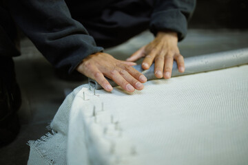 Part of craftswoman doing frame for rug in workshop