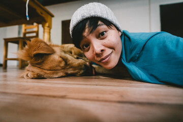A real Asian man takes a selfie with a year-old golden retriever. The dog is licking its owner's...