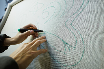 Obraz premium Part of craftswoman drawing on carpet canvas in workshop