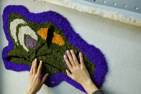 Part of craftswoman checking rug on canvas in workshop 