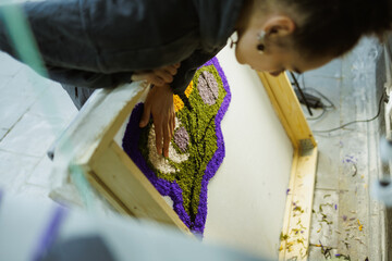 African american craftswoman holding frame with rug on canvas