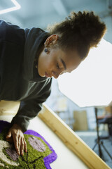 African american craftswoman checking handmade rug in workshop