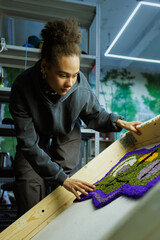 African american craftswoman checking handmade rug in workshop