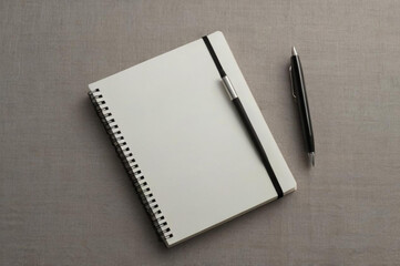 White notebook and black pen on grey fabric surface, top view 