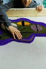 Part of african american craftswoman checking handmade rug 