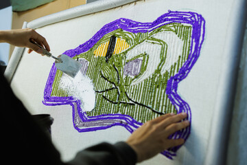 Cropped shot of craftswoman fixing rug on canvas with glue