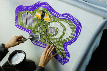 Part of craftswoman fixing threads of handmade rug with glue
