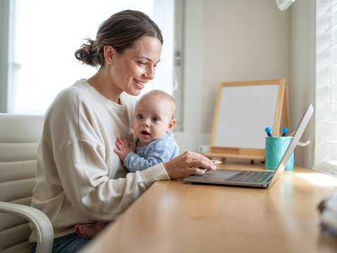 Working Mother Balancing Baby and Laptop at Home Office