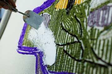 Partial shot of craftswoman fixing threads on rug with glue