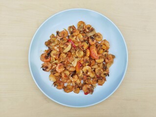 Stir-fried sweet and spicy shrimp on white plate with wooden table background, Flat lay 