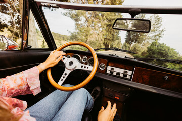 Woman driving vintage convertible car on country road
