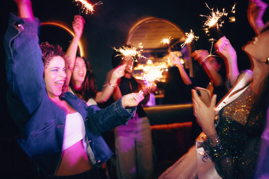 Group of friends celebrating with sparklers at a vibrant night out event
