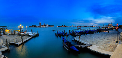 Gondolas resting in venice at blue hour with san giorgio maggiore church