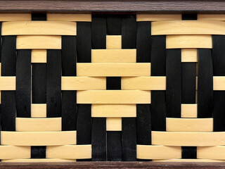 Close up of beautiful hand woven synthetic rattan texture in natural black and brown yellow colors. Wicker art or rattan weaving art in diamond pattern. Seamless texture.