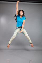 A young woman confidently poses wearing blue t-shirt, distressed denim jeans, heels, showcasing a casual urban style with charm and elegance, suitable for haircare, freedom, self-expression project