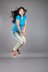 A young woman confidently poses wearing blue t-shirt, distressed denim jeans, heels, showcasing a casual urban style with charm and elegance, suitable for haircare, freedom, self-expression project