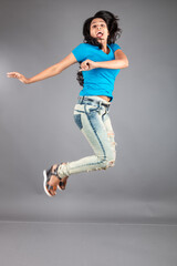 A young woman confidently poses wearing blue t-shirt, distressed denim jeans, heels, showcasing a casual urban style with charm and elegance, suitable for haircare, freedom, self-expression project
