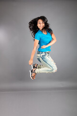 A young woman confidently poses wearing blue t-shirt, distressed denim jeans, heels, showcasing a casual urban style with charm and elegance, suitable for haircare, freedom, self-expression project