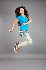 A young woman confidently poses wearing blue t-shirt, distressed denim jeans, heels, showcasing a casual urban style with charm and elegance, suitable for haircare, freedom, self-expression project