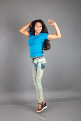 A young woman confidently poses wearing blue t-shirt, distressed denim jeans, heels, showcasing a casual urban style with charm and elegance, suitable for haircare, freedom, self-expression project
