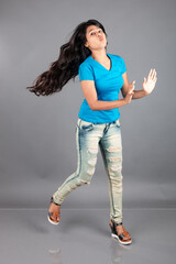 A young woman confidently poses wearing blue t-shirt, distressed denim jeans, heels, showcasing a casual urban style with charm and elegance, suitable for haircare, freedom, self-expression project