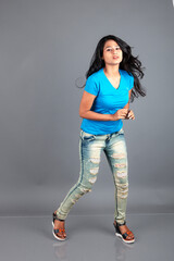 A young woman confidently poses wearing blue t-shirt, distressed denim jeans, heels, showcasing a casual urban style with charm and elegance, suitable for haircare, freedom, self-expression project