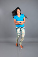 A young woman confidently poses wearing blue t-shirt, distressed denim jeans, heels, showcasing a casual urban style with charm and elegance, suitable for haircare, freedom, self-expression project