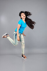 A young woman confidently poses wearing blue t-shirt, distressed denim jeans, heels, showcasing a casual urban style with charm and elegance, suitable for haircare, freedom, self-expression project
