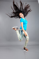 A young woman confidently poses wearing blue t-shirt, distressed denim jeans, heels, showcasing a casual urban style with charm and elegance, suitable for haircare, freedom, self-expression project