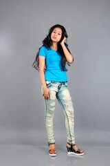 A young woman confidently poses wearing blue t-shirt, distressed denim jeans, heels, showcasing a casual urban style with charm and elegance, suitable for haircare, freedom, self-expression project